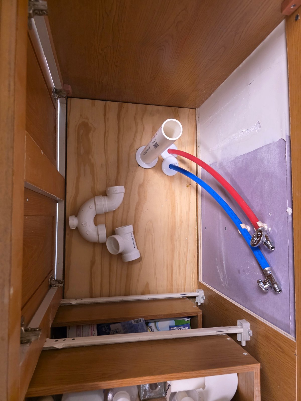 Plumbing pipes, shut-off valves and supply lines installed by Clark's Heating and Cooling inside a cabinet